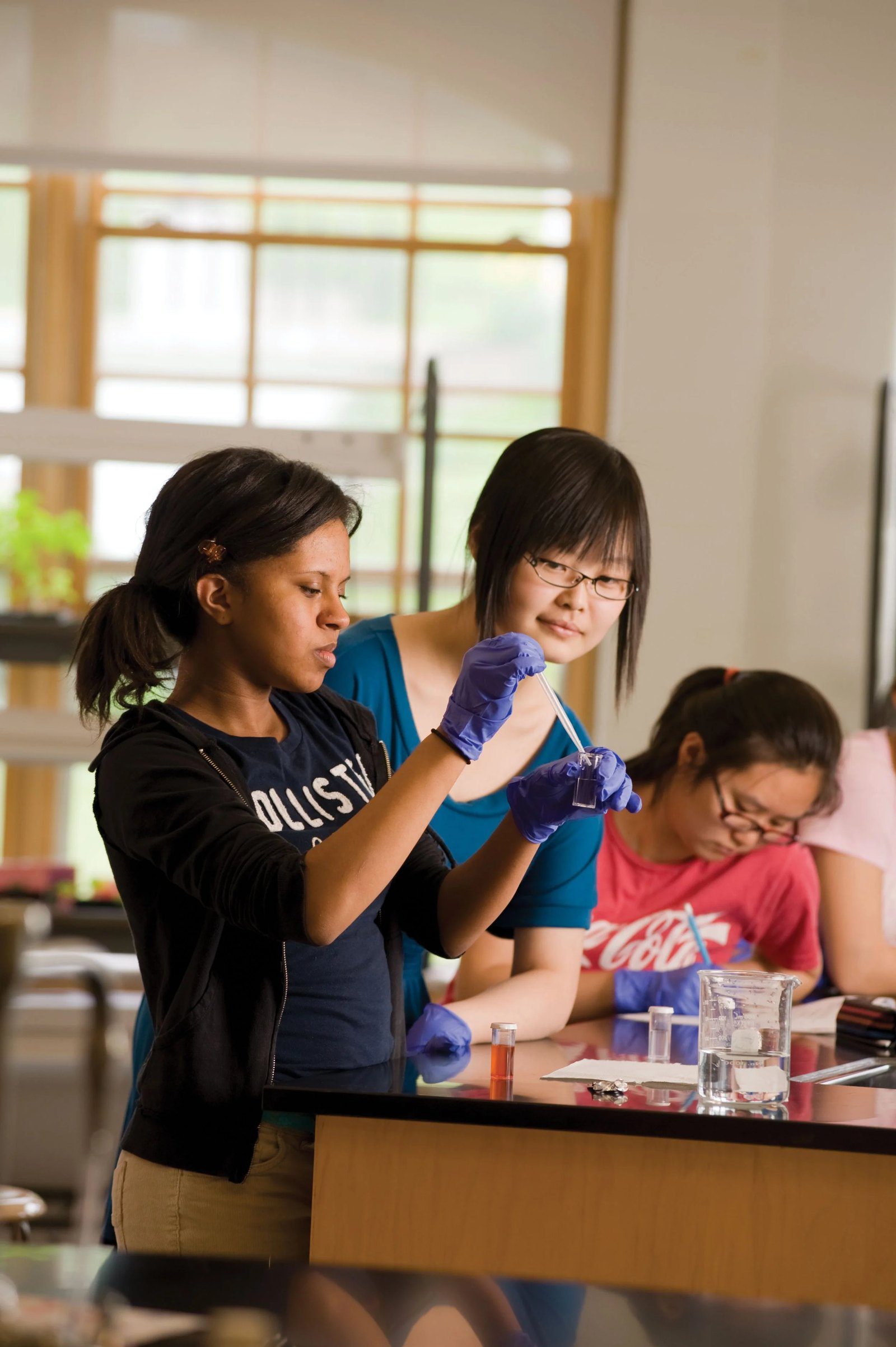 Alumnas con guantes en un laboratorio de ciencias durante un experimento